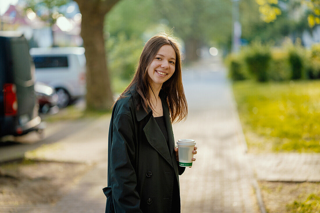 Smiling teenage girl holding cup of coffee