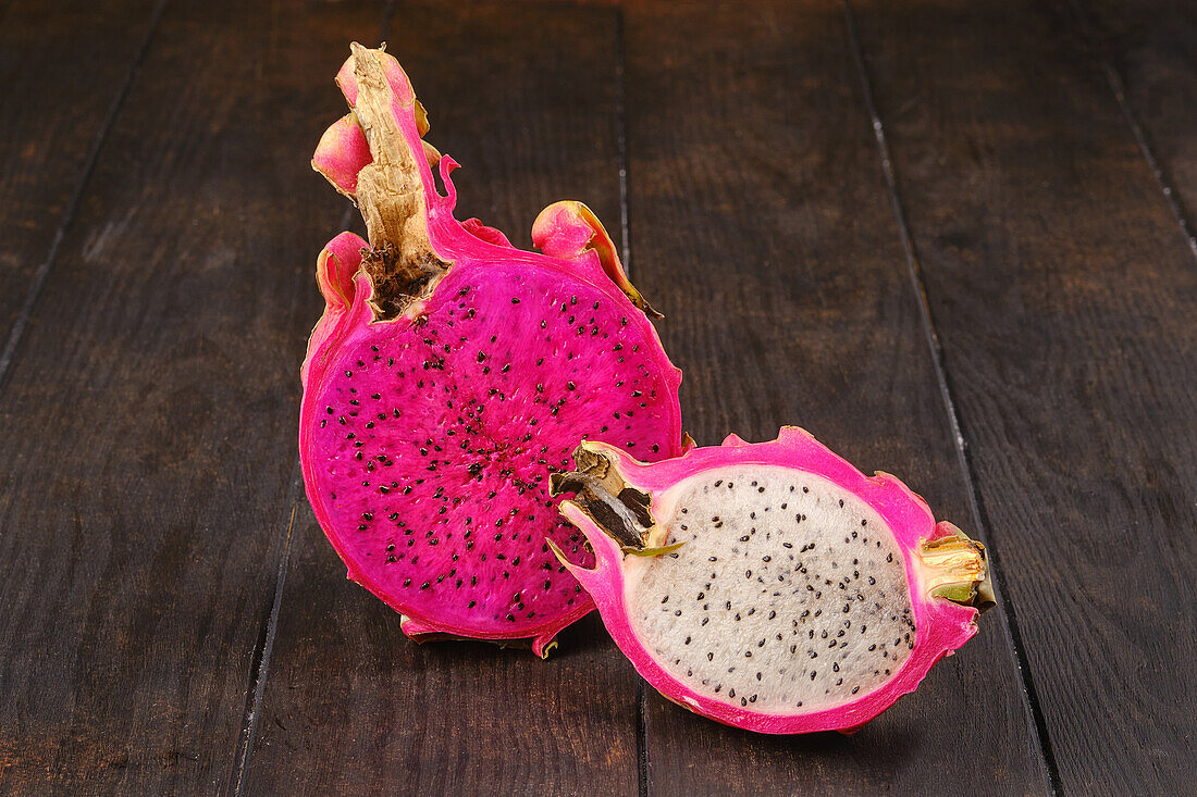 Whole and halved dragon fruit on a wooden table