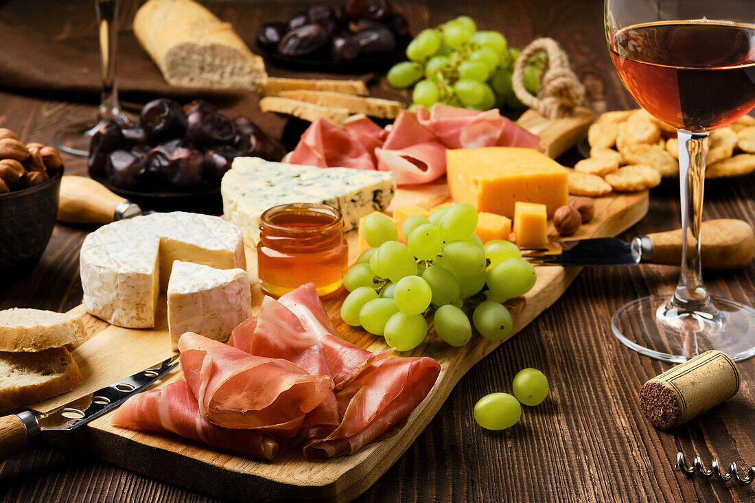 Cheese platter with prosciutto, grapes, honey and wine