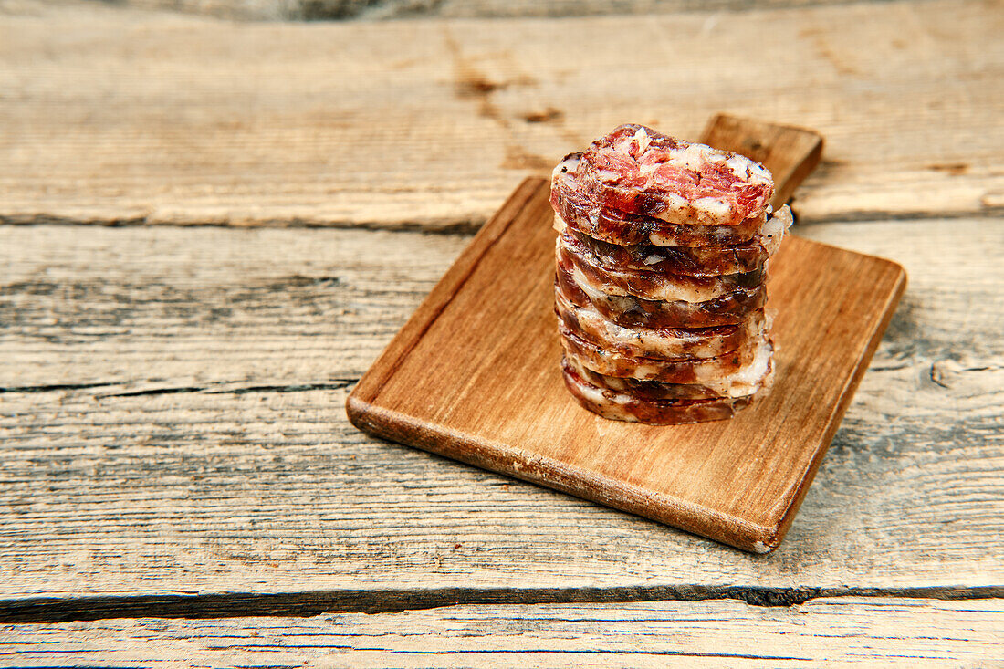 Grobe Rindersalami in Scheiben auf Holzbrett