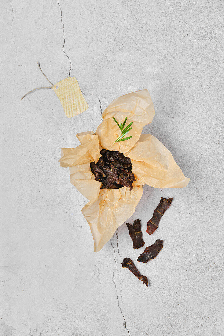 Dried venison with rosemary sprig on wrapping paper