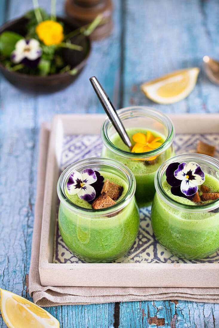 Herb soup with croutons and edible flowers