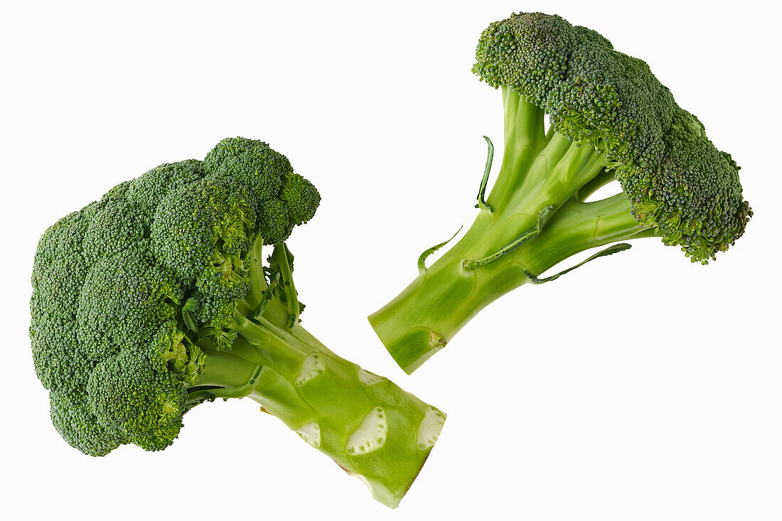 Two broccoli against a white background