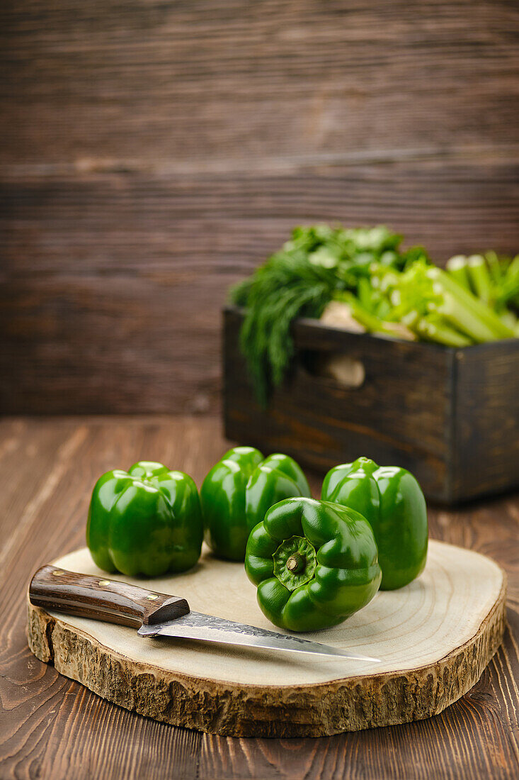 Grüne Paprika mit Messer auf Holzschneidebrett