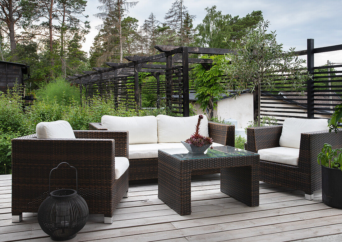 Garten-Lounge mit Polyrattan-Möbeln und Holzdeck im Grünen