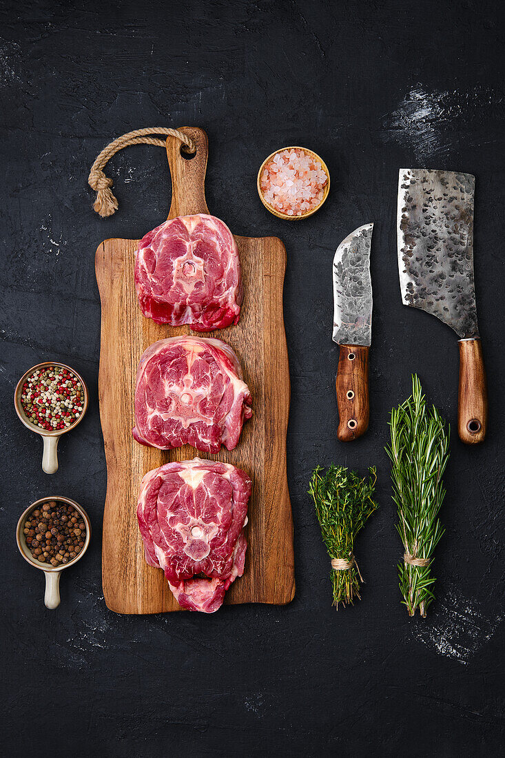 Raw lamb neck steak with herbs and spices on a chopping board