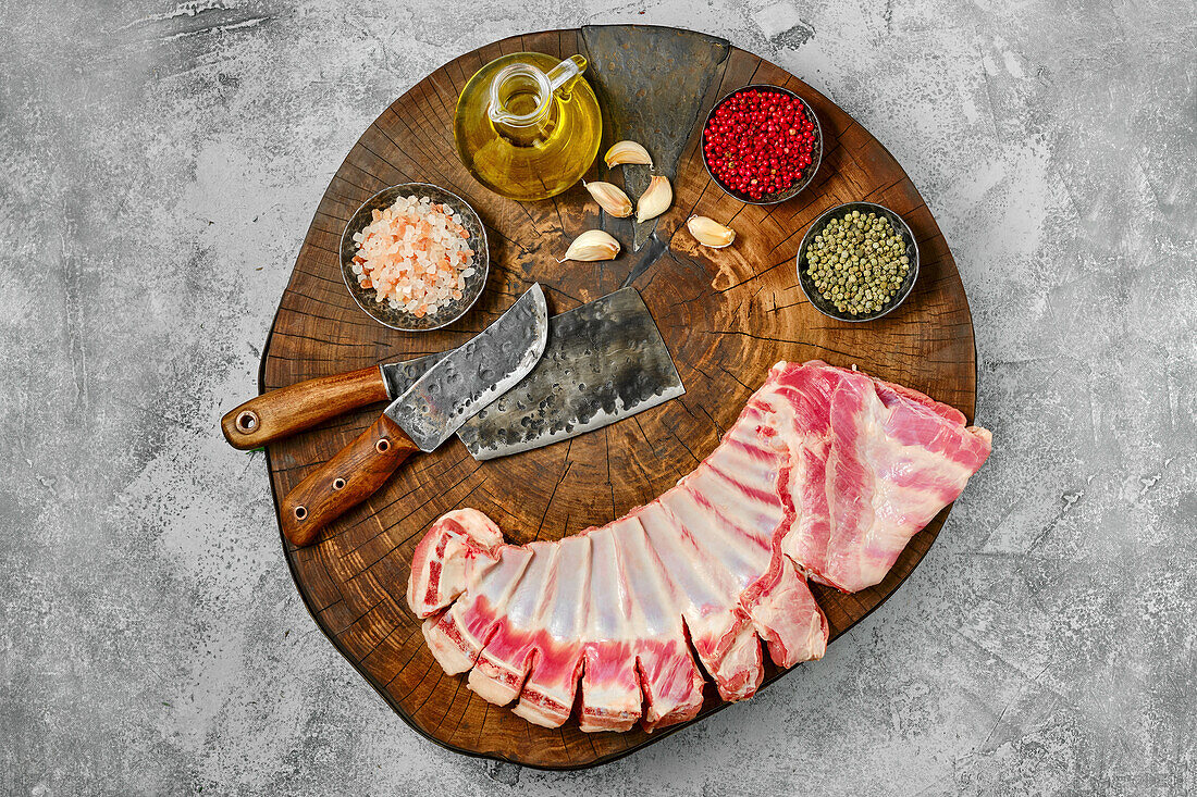 Raw lamb ribs with spices and olive oil on a wooden board