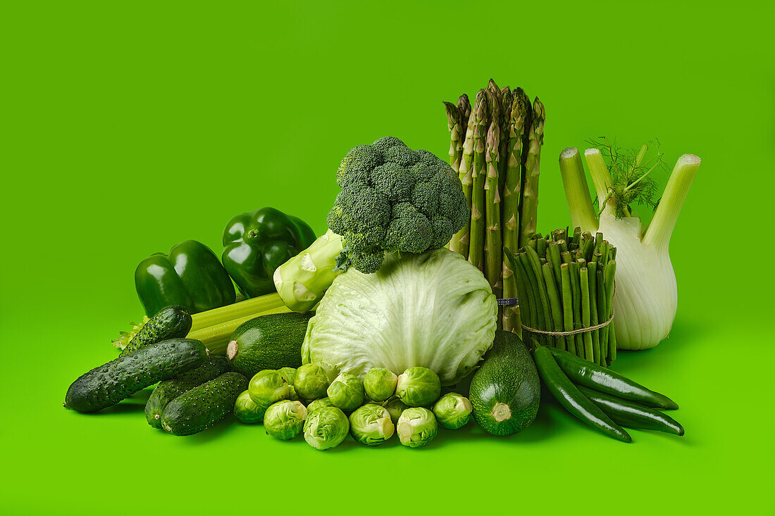 Various green vegetables against a green background