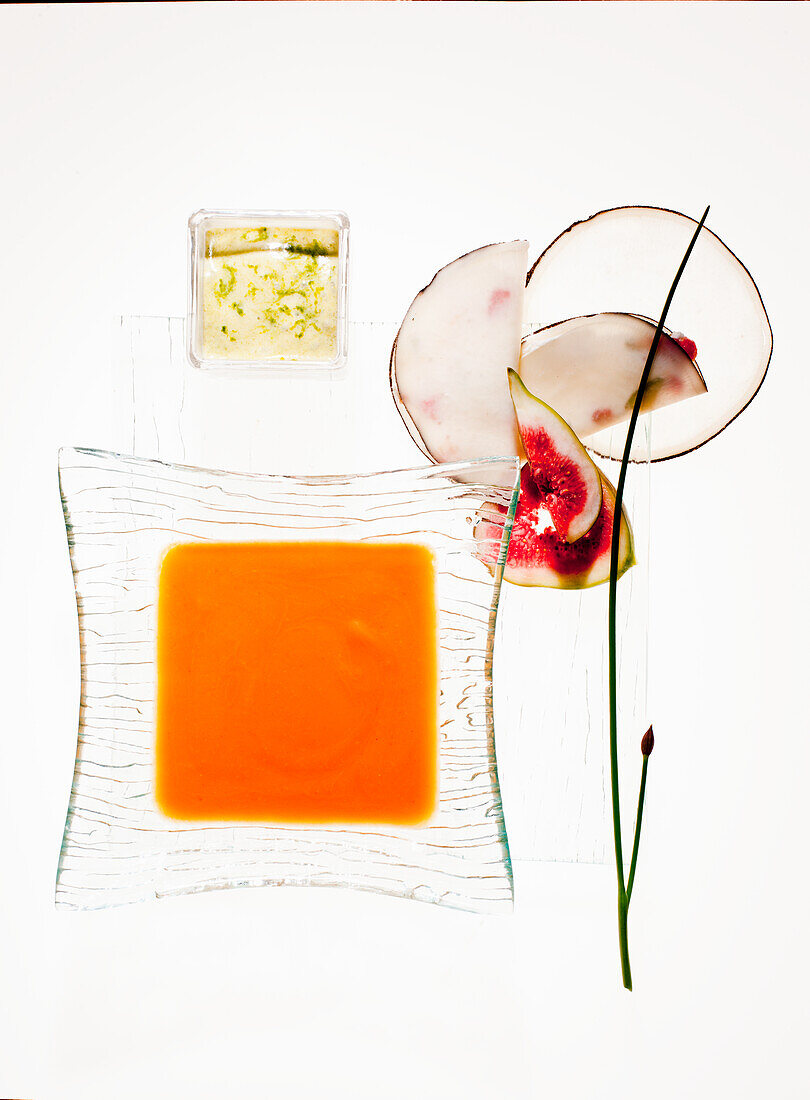 Orange-coloured soup with figs and chives