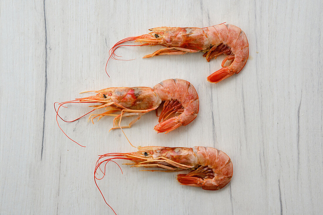 Three cooked prawns on a light-coloured base