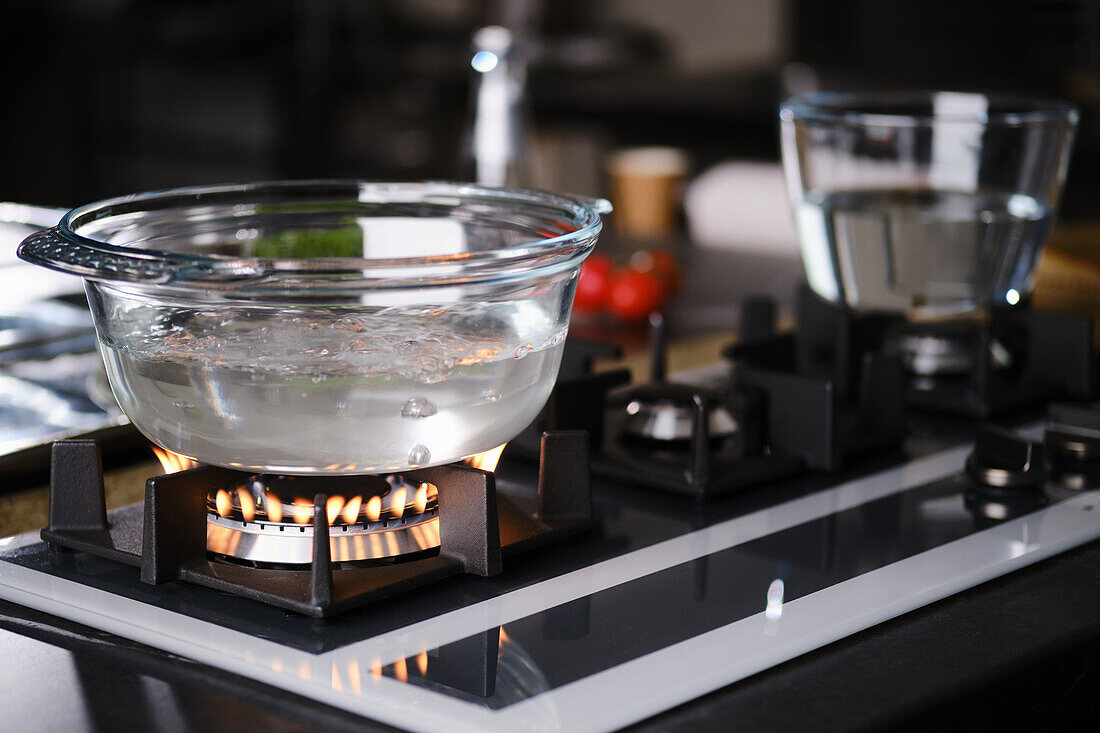 Water boiling in a glass jar on a gas hob