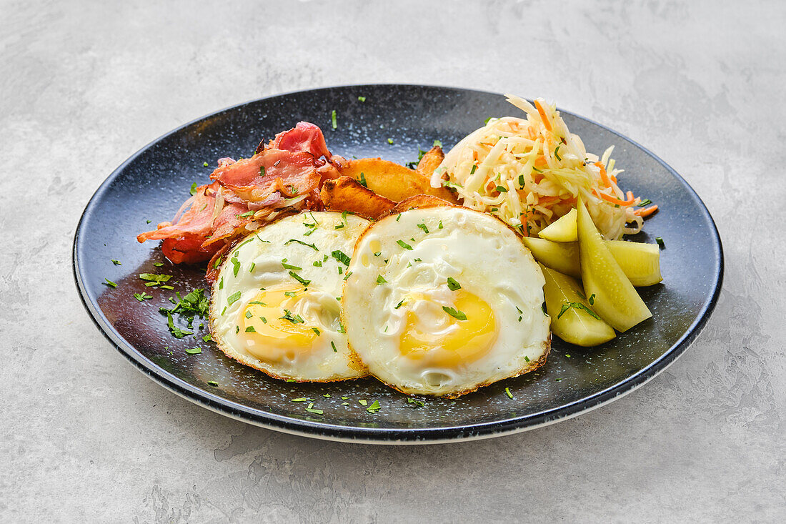 Fried eggs with bacon, potato wedges and coleslaw