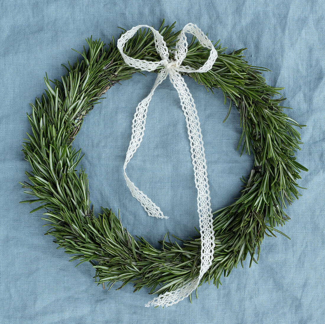 Tied rosemary wreath (Rosmarinus officinalis) with white loop on fabric background