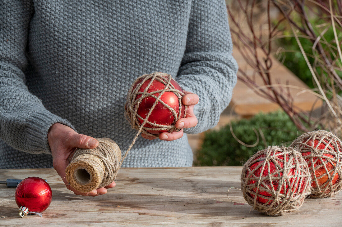 Kugeln mit Gartenschnur umwickeln, Frau bastelt Christbaumkugeln, close-up