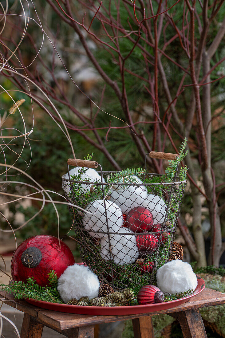 Christbaumkugeln und Schneebälle aus Webpelz im Drahtkorb, Nadelzweige auf Teller, Weihnachtsdekoration