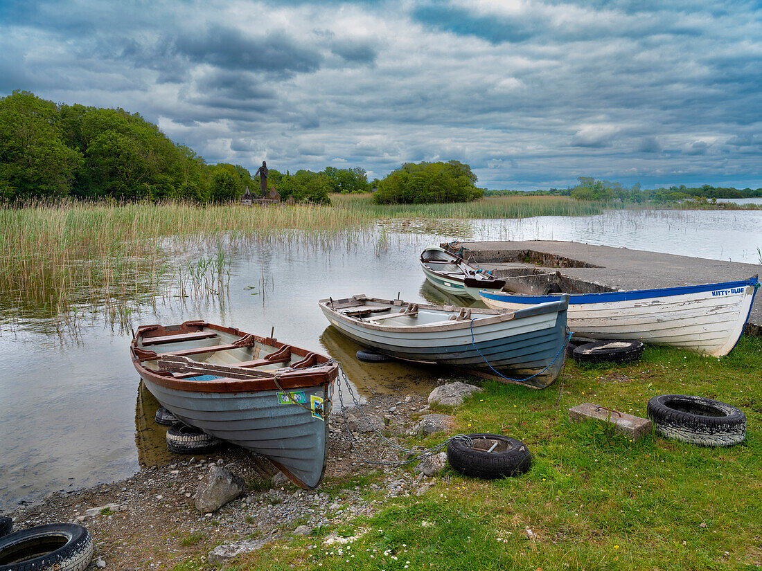Boats await skippers on Lough Carra, County Mayo, Ireland. Shrine watches over the fishermen.