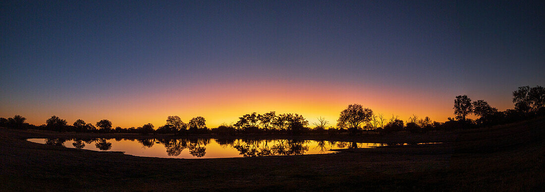 Colorful sunset at watering hole. Camelthorn Lodge. Hwange National Park. Zimbabwe.