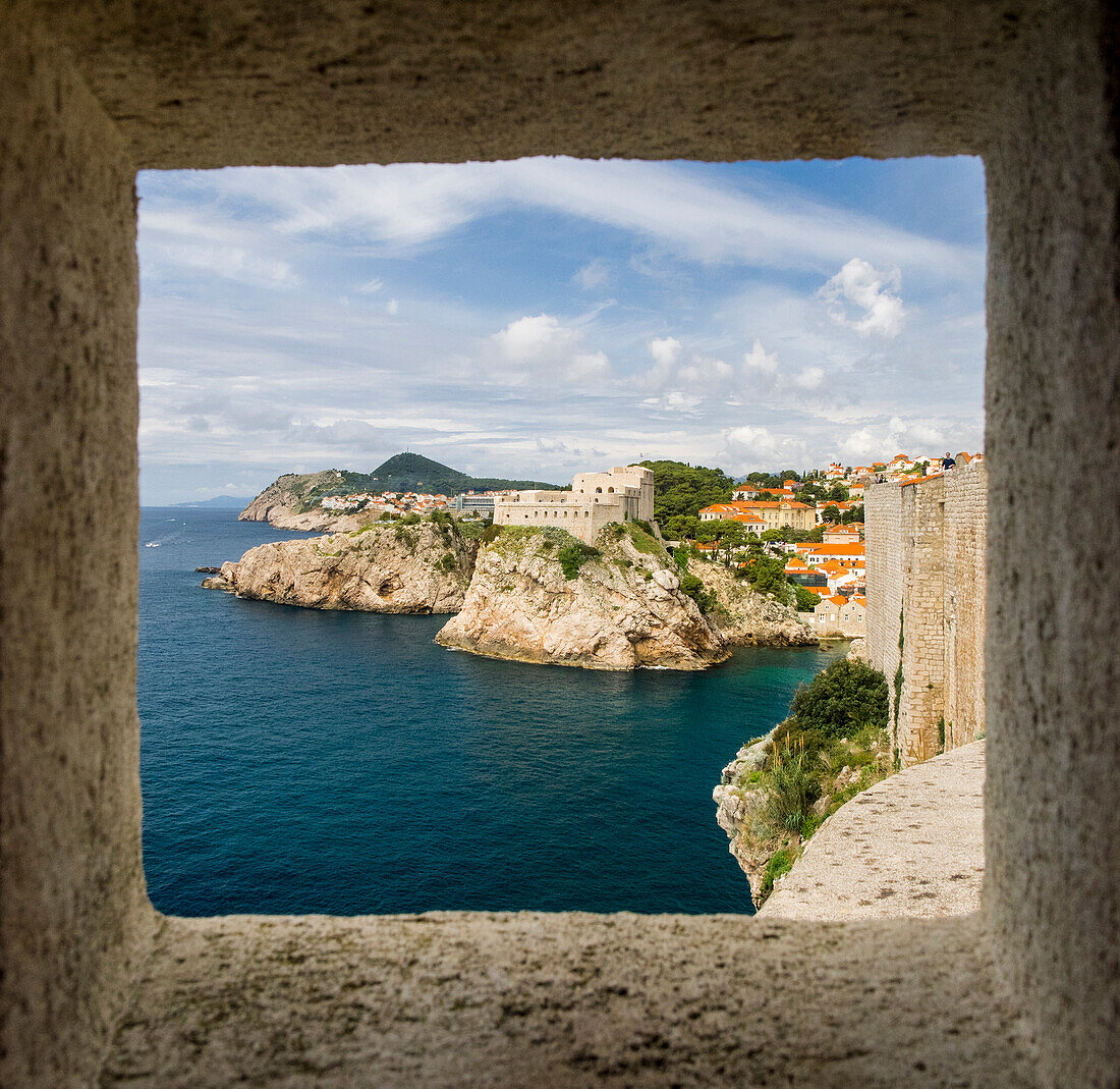 Croatia, Dubrovnik. Ancient fortress on the cliff edge of Dubrovnik protects the port as seen from through a window on the wall surrounding the city.