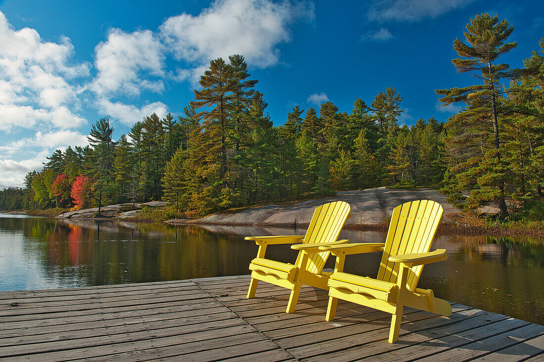 Kanada, Ontario, Grundy Lake Provincial Park. Muskoka-Stühle auf einem Steg im See.