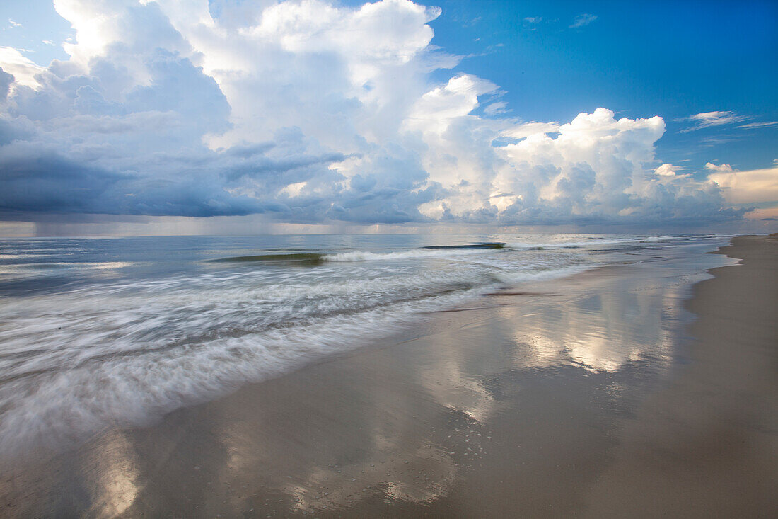 USA, Georgia, Tybee Island. Sunrise with clouds and reflections along the coast.