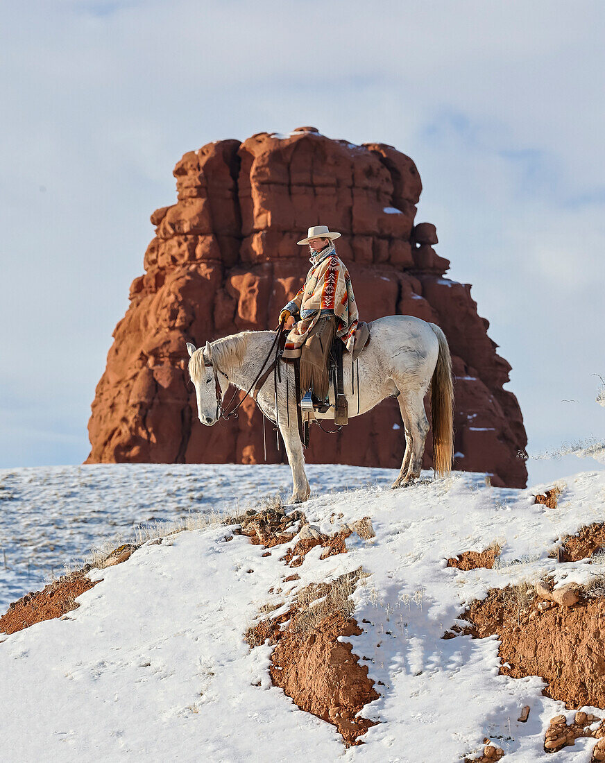 USA, Wyoming. Hideout Ranch cowgirl on horseback riding on ridgeline snow. (PR,MR)