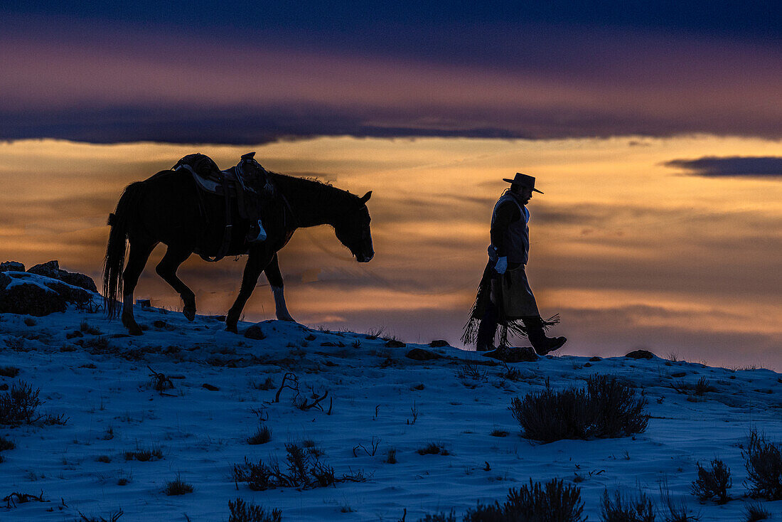USA, Wyoming. Hideout Horse Ranch, wrangler and horse at sunset. (MR,PR)