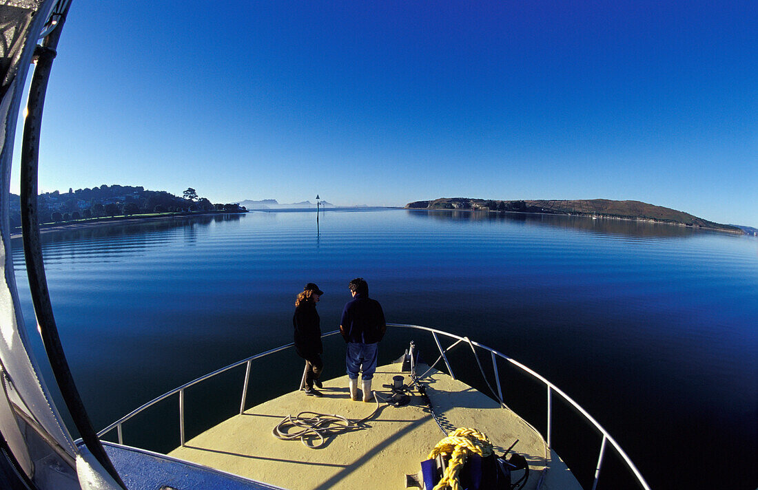 Neuseeland, Northland, Paar auf dem Vordeck bewundert die friedliche Ruhe eines windstillen Morgens; Whangarei Harbor