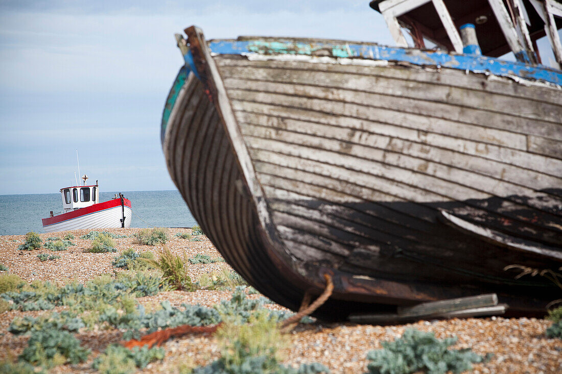 Alte Fischerboote, Netze und Fischerhütten sind ein häufiger Anblick auf den Kiesbänken von Dungeness in Kent, Großbritannien