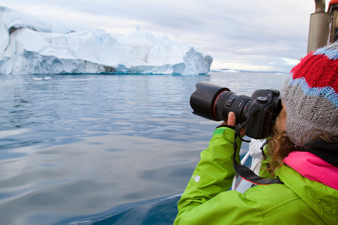 Frau auf mitternächtlicher Fahrt um den Ilulissat Eisfjord, eine der Unesco Weltkulturerbestätten. Grönland.