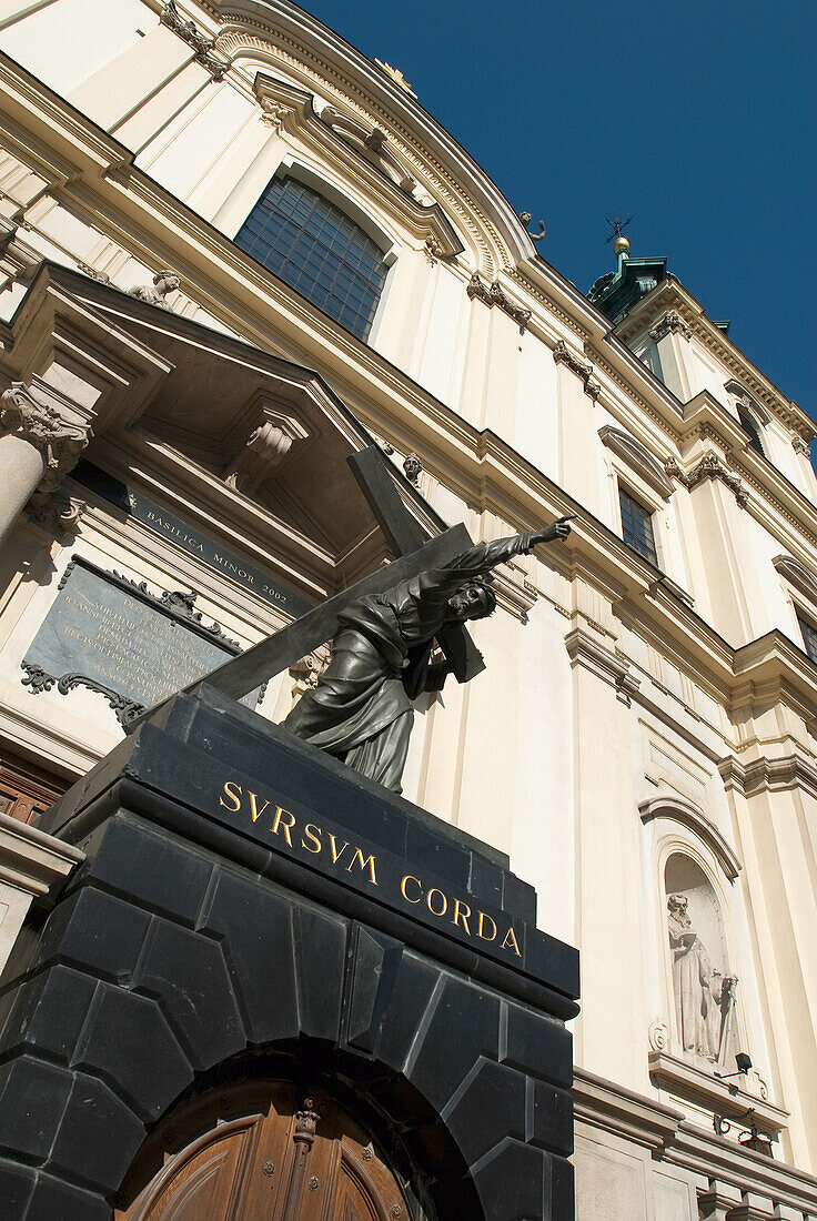 Statue of Christ bearing his cross in front of the baroque-styled Holy Cross church on the Royal Route, Krakowskie Przedmiescie, Poland