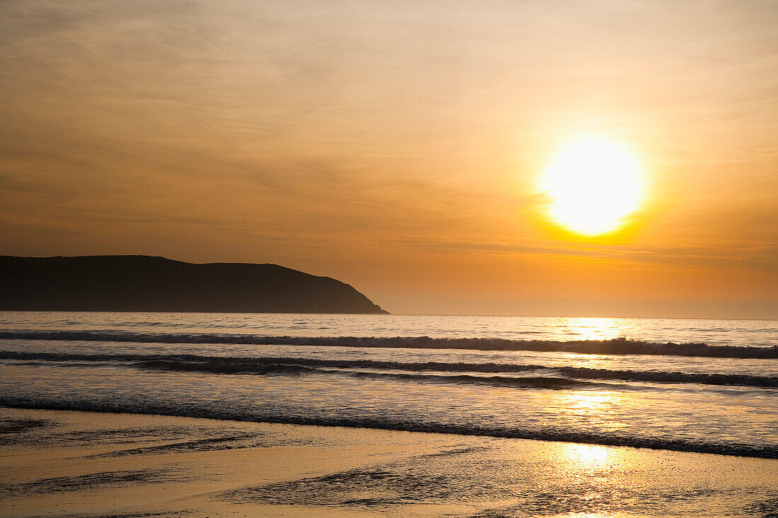 Sonnenuntergang über dem Meer und Strand in Putsborough Sands, Nord-Devon, Großbritannien