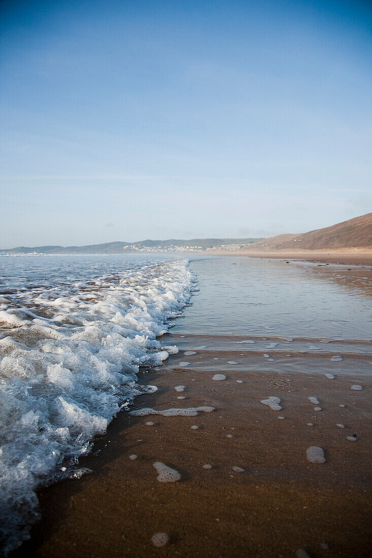 Waves Lapping On The Sandy Beach, On A Calm Sunny Day At Putsborough Sands, North Devon, Uk