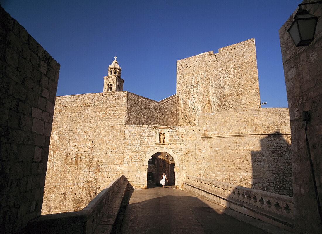 Frau geht durch das östliche Tor zu den Stadtmauern von Dubrovnik früh am Morgen, Kroatien.
