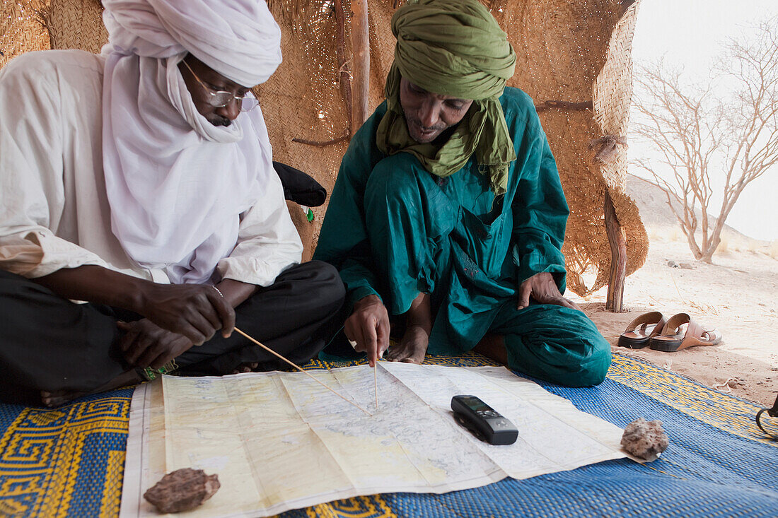 Niger, Sahara-Wüste, Steilhang von Tiguidit; Region Agadez, Tuareg-Männer prüfen die GPS-Punkte der Route