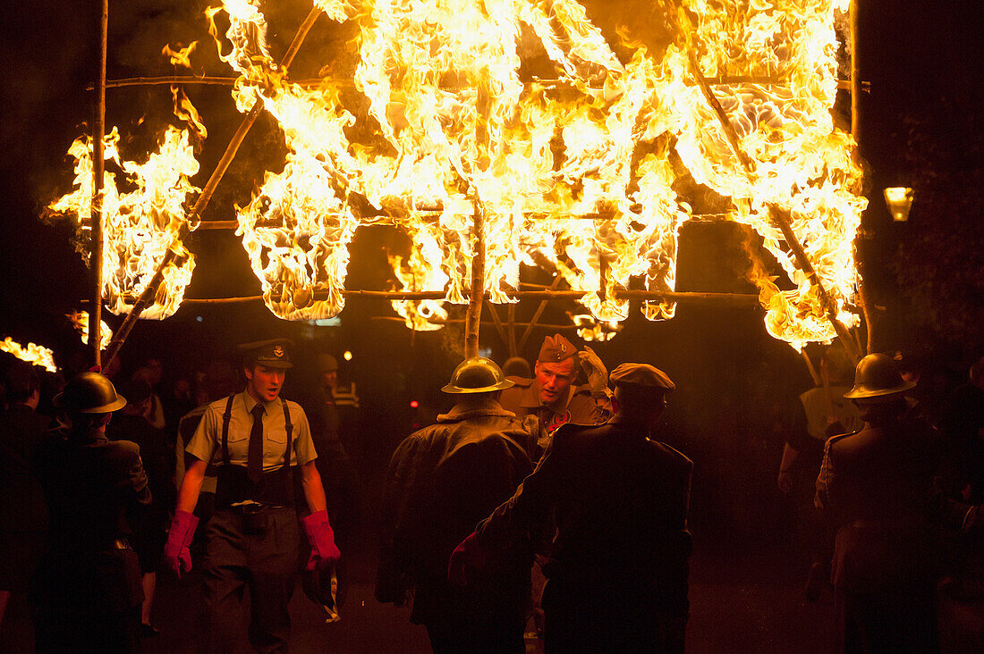 Leute von der East Hoathly & Halland Carnival Society tragen ein großes brennendes Banner durch East Hoathly in der Nacht des Lagerfeuers, East Sussex, Großbritannien