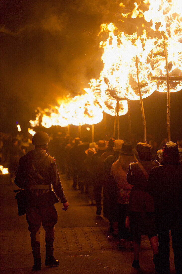 Leute von der East Hoathly & Halland Carnival Society tragen ein großes brennendes Banner durch East Hoathly in der Nacht des Freudenfeuers, East Sussex, Großbritannien