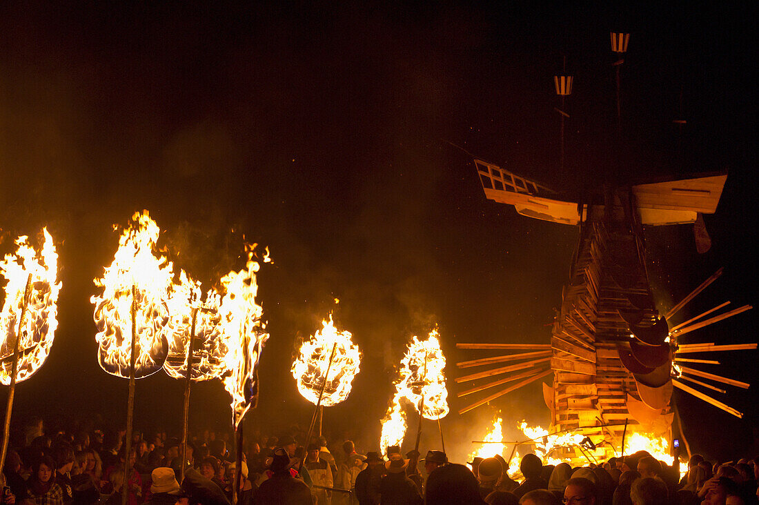 People Carrying Large Banner In Front Of 31 Burning Poppies On Bonfire Night To Commemorate The 31 Villagers Lost In The World Wars, East Hoathly, East Sussex, Uk