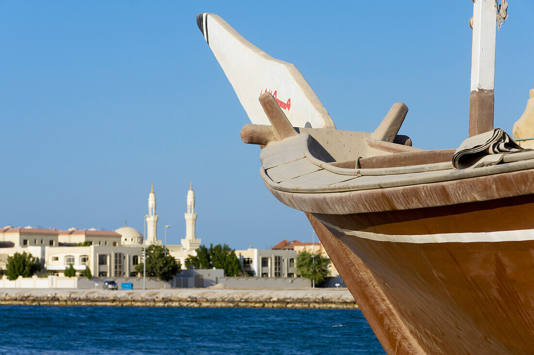 Vereinigte Arabische Emirate, Blick auf Segelboot mit Stadtsilhouette in der Ferne; Ras Al Khaimah