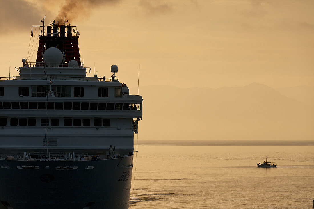 Griechenland, Kleines Fischerboot neben großem Kreuzfahrtschiff in der Morgendämmerung; Korfu