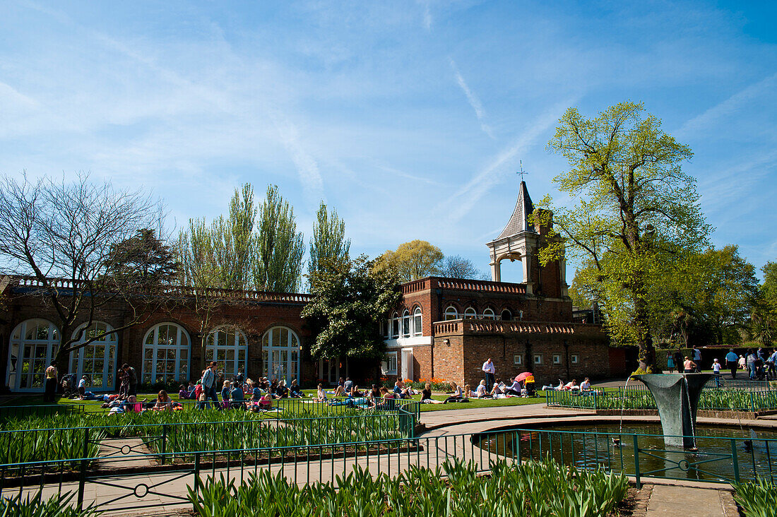 Menschen beim Sonnenbaden an einem Frühlingstag im Holland Park, West London, London, Großbritannien