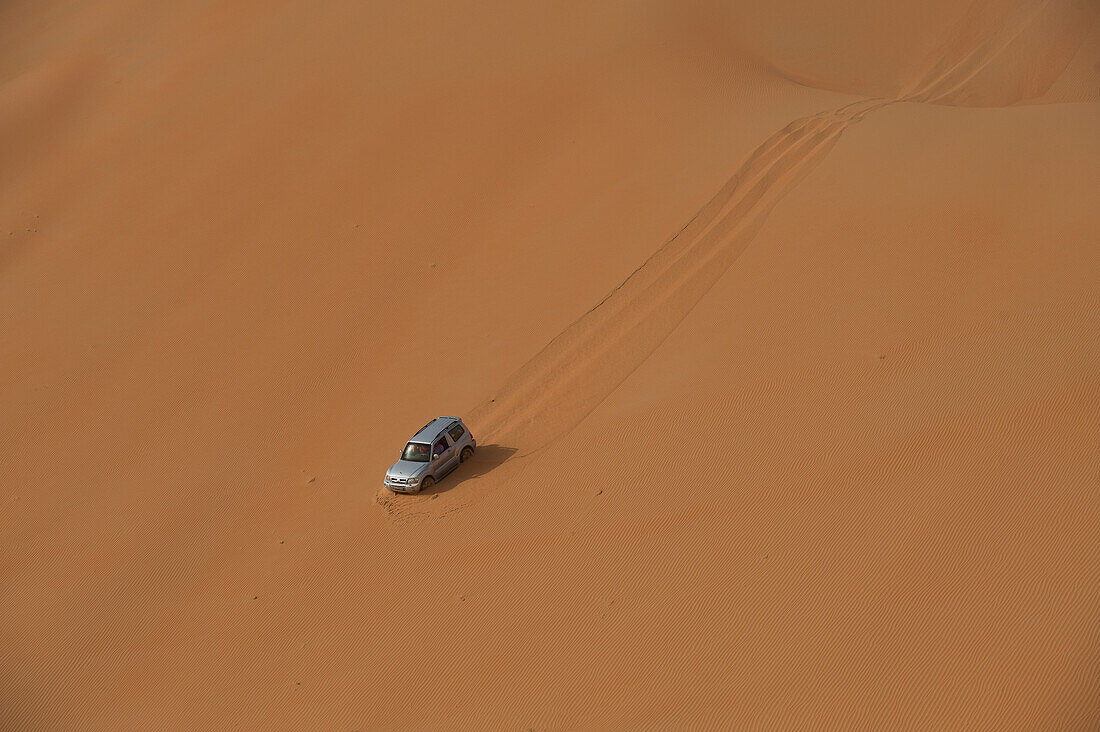 UAE, Abu Dhabi, Geländewagen fährt steile Sanddüne hinunter; Liwa