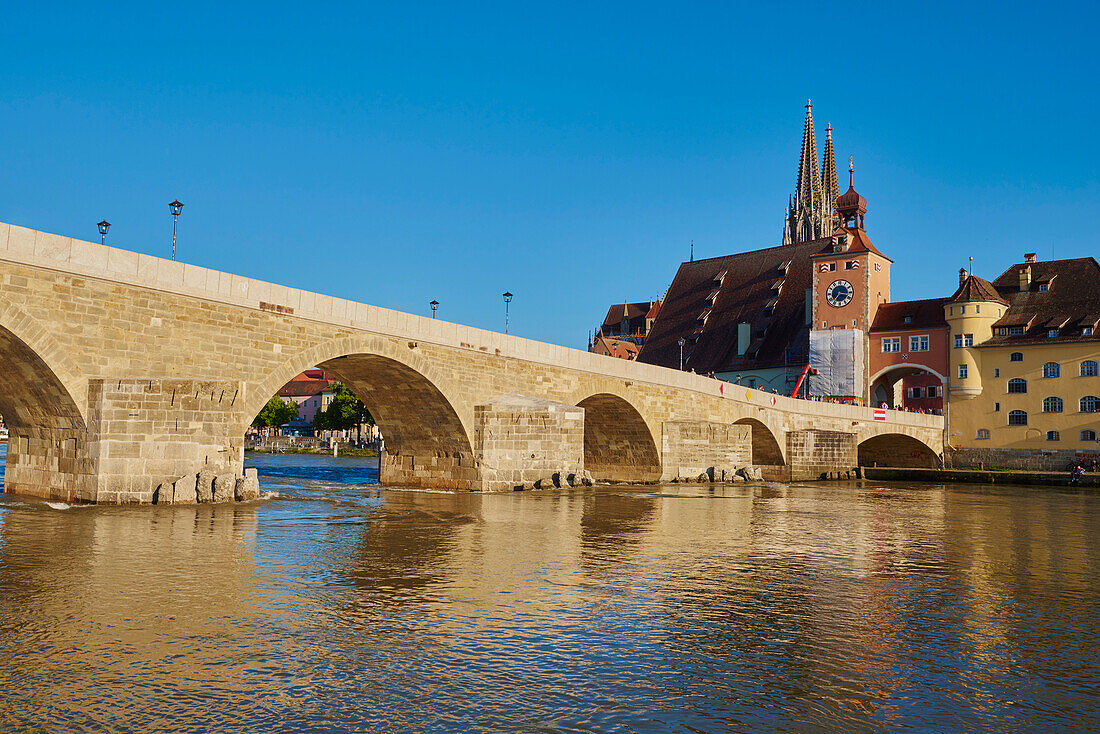 Alte Steinbrücke aus dem 12. Jahrhundert und der gotische Dom St. Peter (Regensburger Dom) an der Donau in der Altstadt von Regensburg bei blauem Himmel im Herbst; Regensburg, Oberpfalz, Bayern, Deutschland