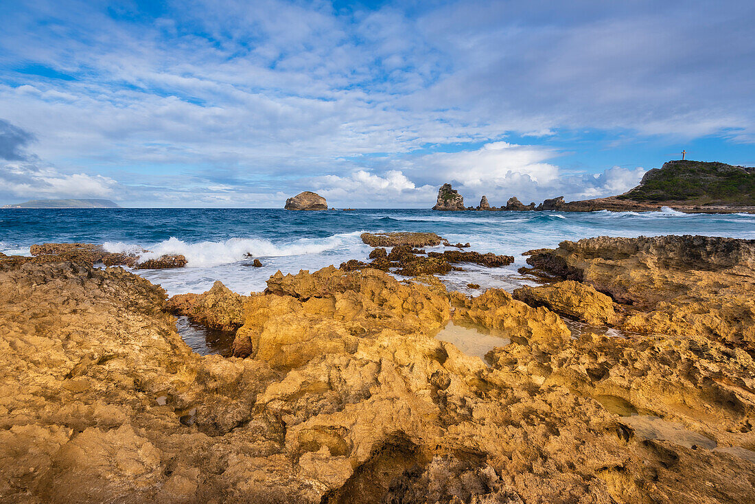 Wellen brechen an den Felsformationen entlang der Küste von Grande-Terre mit dem Grand-Croix in der Ferne an der Spitze der Pointe des Chateaux; Guadeloupe, Französisch-Westindien
