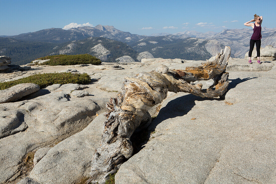 Two hikers take a moment to stretch atop Sentinel Dome, a rocky peak that offers stunning views to the Yosemite Valley.; Yosemite National Park, California