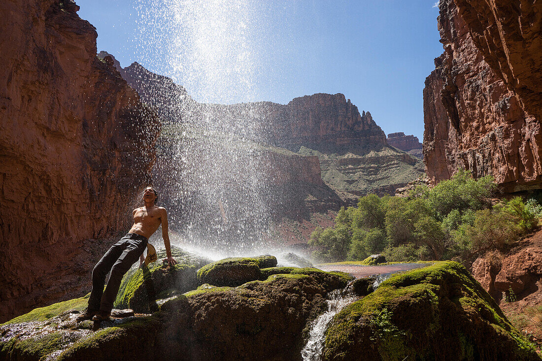 Ein Wanderer kühlt sich unter den Ribbon Falls am North Kaibab Trail ab; Grand Canyon National Park, Arizona