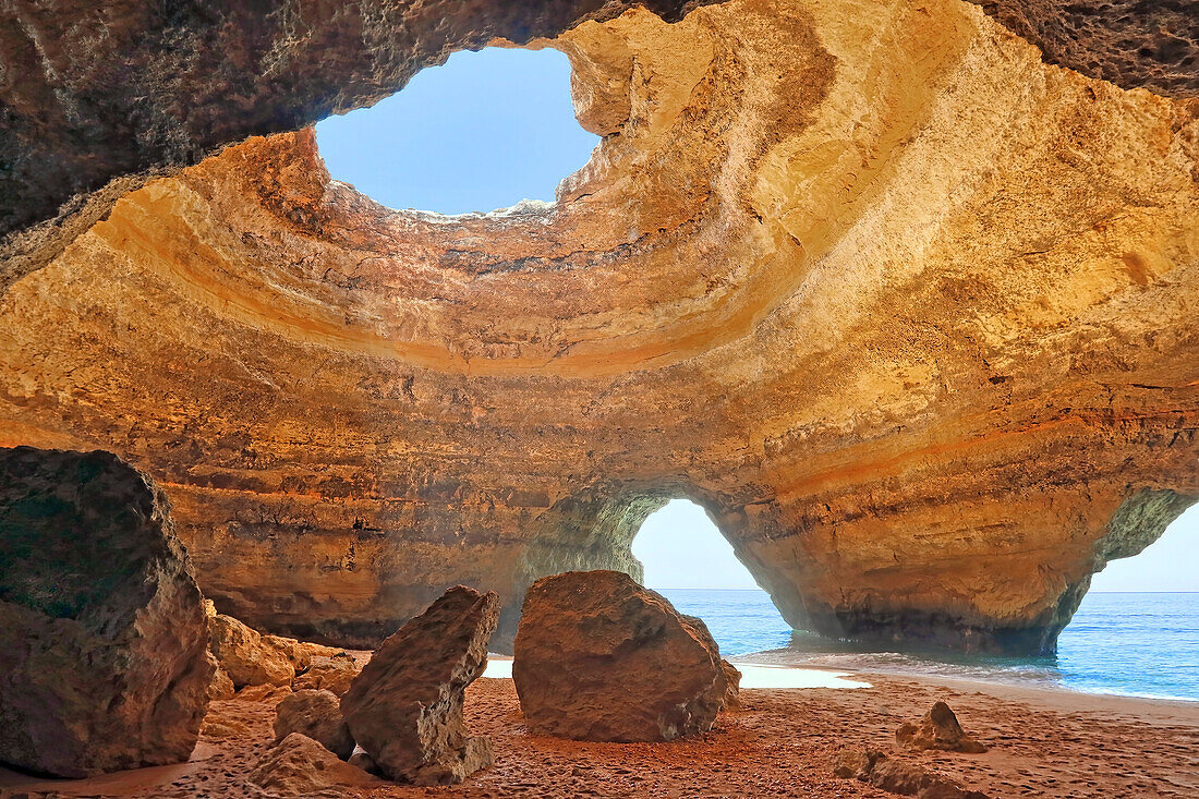 Sandsteinfelsen in der Benagil-Höhle, das Innere einer Meereshöhle an der Meeresküste der Algarve mit Sonnenlicht, das durch eine Öffnung scheint; Algarve, Lagoa, Iberische Halbinsel, Portugal