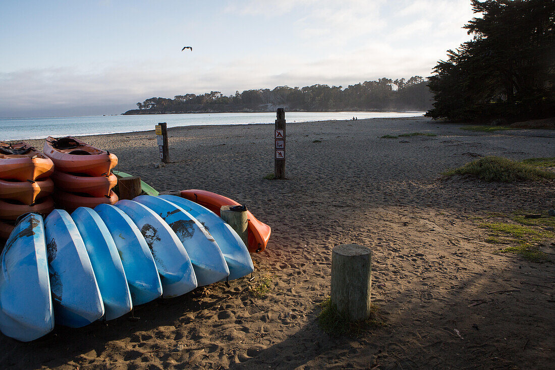 Colorful kayaks stacked on a beach at San Simeon Cove.; San Simeon Cove, San Simeon, California