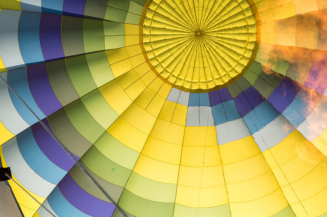 A flame is visible inside a colorful hot air balloon.; Winters, California