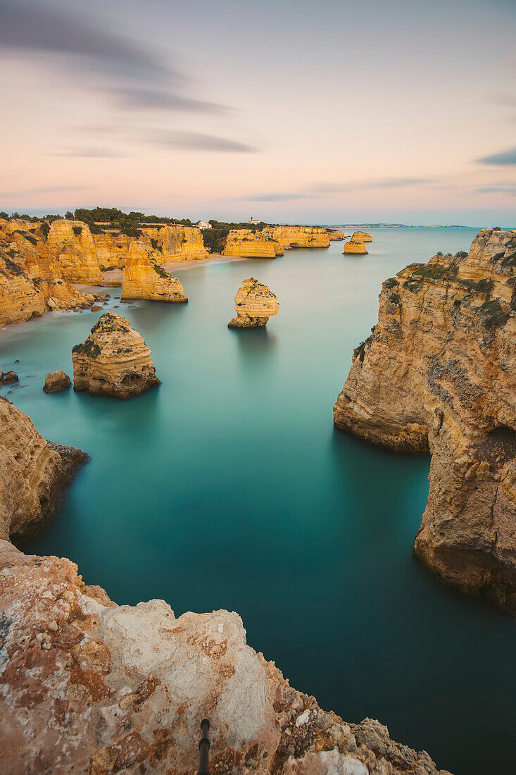 Ikonische Felsformationen und türkisfarbenes Wasser des Atlantiks am Praia da Marinha entlang der Atlantikküste in Caramujeira, Teil der Gemeinde Lagoa, bei Sonnenuntergang; Algarve, Bezirk Faro, Portugal