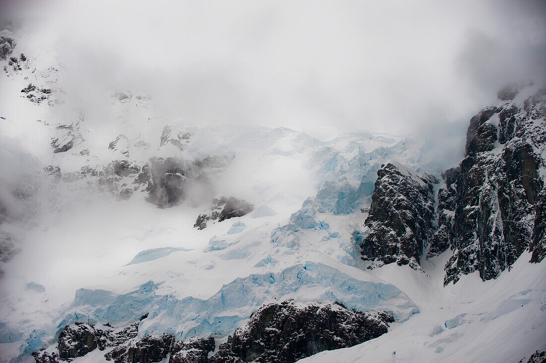 Gewitterwolken über dem felsigen, eisgepackten Gletscher am Lemaire Channel entlang der Antarktischen Halbinsel; Antarktische Halbinsel, Antarktis